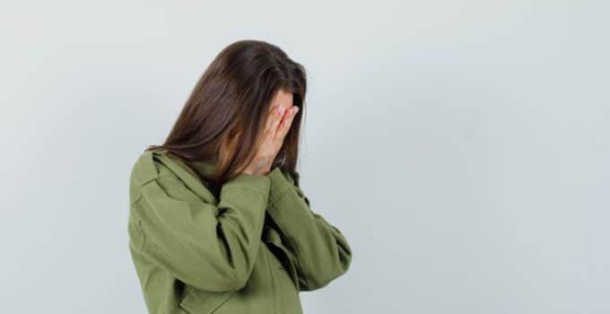 young woman covering hands her face green jacket looking sad front view space text 176474 38056