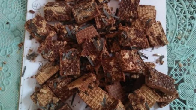 Man geeft chocoladewafels verwerkt met scheermesjes en nietjes aan jonge kinderen